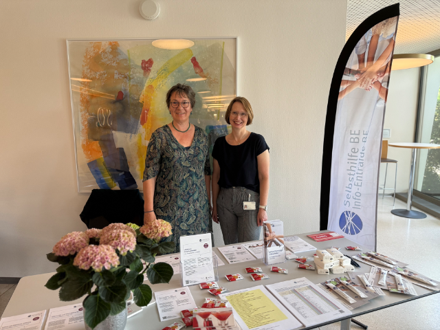 Evelyn Müller (SRO AG) und Gabriela Kühni (Selbsthilfe BE) am gemeinsamen Informationsstand zum Tag der Selbsthilfe am 21. Mai 2026. Auf dem Tisch liegen Broschüren und Informationsmaterialien.