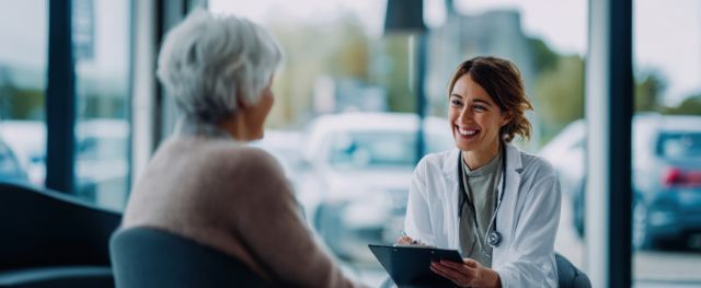 Eine Ärztin führt ein Gespräch mit einem älteren Patienten in einer ruhigen und entspannten Atmosphäre.