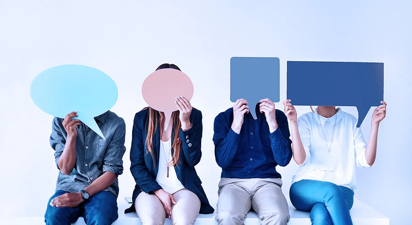 Vier Personen halten bunte Sprechblasen vor Ihren Gesichtern.